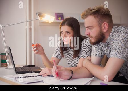 two people, studying together, seriously discussing project or learning. Stock Photo