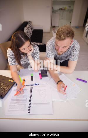 two students learning together, sitting at table in front of papers. shot from high above. Stock Photo