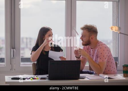 two young people, discussing project or studying together. casually dressed in apartment. Stock Photo