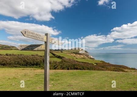 Close up of a sign post pointing toward Golden Cap mountain with Golden Cap mountain in the background Stock Photo