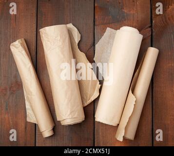 four rolled rolls of brown parchment paper on a wooden background Stock Photo