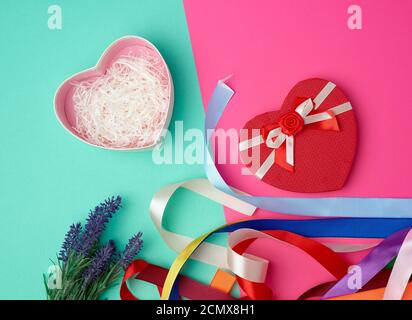 open red heart-shaped gift box with a bow on a pink green background Stock Photo