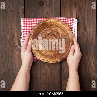 two female hands holding an empty round wooden plate Stock Photo