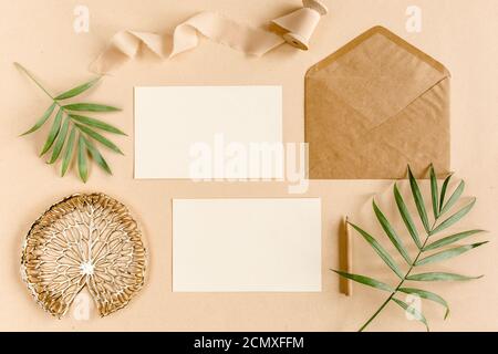 Mockup wedding invitation, blank greeting card and craft envelope, tropical palm leaves. Flat lay, top view. Stock Photo