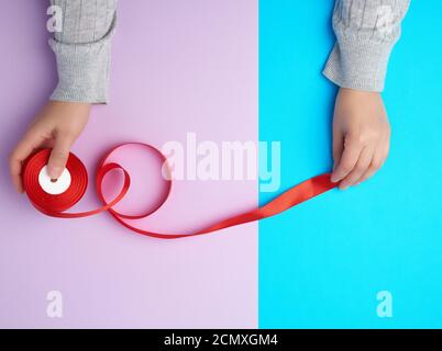two female hands holding a bobbin with a red silk ribbon Stock Photo