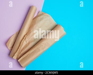 two rolled rolls of brown parchment baking paper on a colored background Stock Photo
