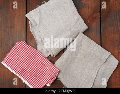 white red checkered kitchen towel and gray linen napkins on a brown wooden background Stock Photo
