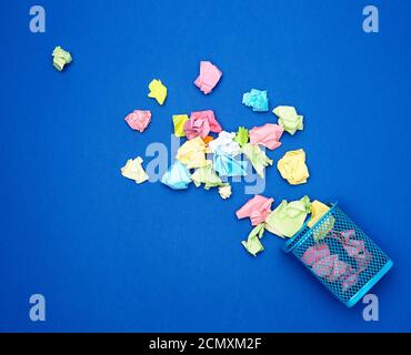 blue metal bucket filled with crumpled multi-colored white paper Stock Photo