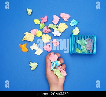 female hand holds a bunch of crumpled multi-colored pieces of paper Stock Photo