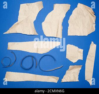 set of various pieces of torn brown crumpled paper on a blue background Stock Photo