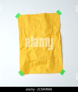 empty yellow crumpled sheet of paper glued with green sticky pieces of paper Stock Photo