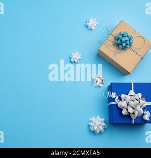 two square gift boxes decorated with ribbons and bows on a blue background Stock Photo