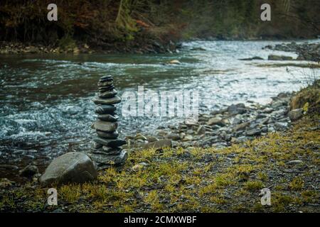 Rocks stacked in a tower at the edge of a river Stock Photo
