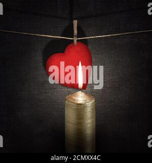 burning candle and red paper heart on a rope over vintage embossed dark backgrounds Stock Photo