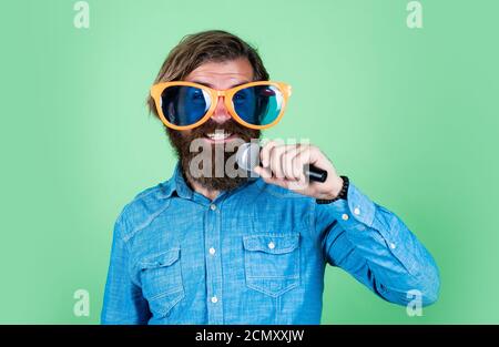 Music is only love looking for words. performer having fun. mature bearded man in funny party glasses sing song. brutal male hipster with microphone. vocal school. favorite music style. Stock Photo