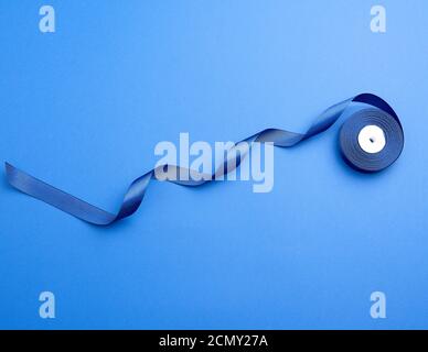 twisted dark blue silk ribbon on a blue background Stock Photo