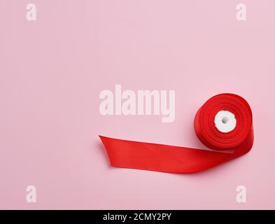 spools with red satin ribbon on a pink background Stock Photo