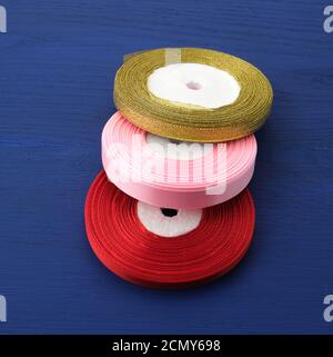 twisted red, pink, golden silk ribbons on a blue background, element for the designer, top view Stock Photo