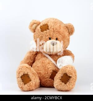 large beige teddy bear with patches sits on a white background Stock Photo