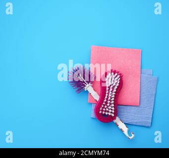 plastic pink brush and square dishwashing rag on a blue background Stock Photo