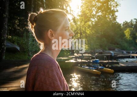 Woman sitting on dock, looking out at Lake Kabetogama in Voyageurs National Park, Minnesota Stock Photo