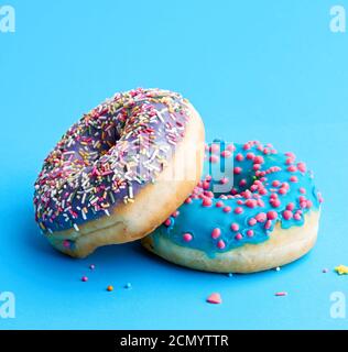 two round baked donut with colored sugar sprinkles and with blue sugar icing Stock Photo