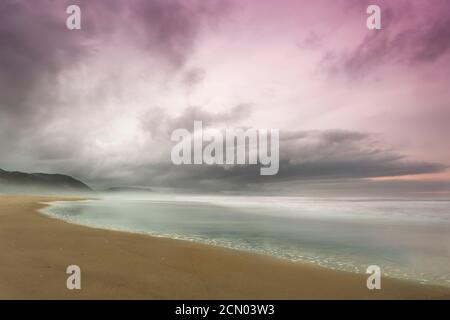 the beach in a dramatic sky and soft waves captured Stock Photo