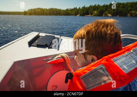 Boy riding in the bow of a boat on Lake Kabetogama in Voyageurs National Park, Minnesota Stock Photo