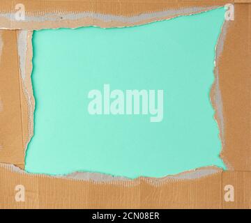 torn edges of corrugated brown cardboard paper on a green background Stock Photo