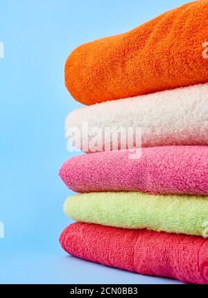 stack of colored cotton terry folded towels on a blue background Stock Photo