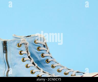 pair of light blue worn textile sneakers with laces and zippers on a ...