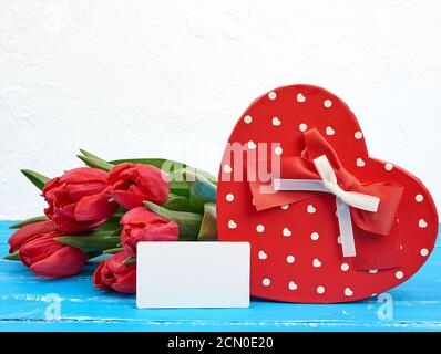 empty rectangular white paper business card, bouquet of red tulips and a heart-shaped cardboard box Stock Photo