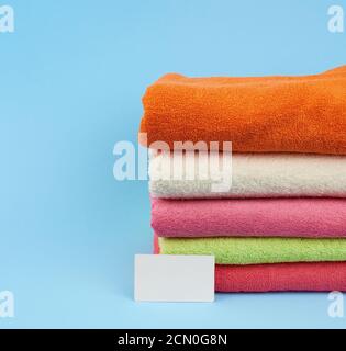 stack of multi-colored terry towels to wipe the body after a shower and a white blank paper business Stock Photo
