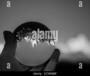 Black and white filter on a hand holding lens ball with a reflection of Patagonia Mount Fitz Roy. Stock Photo