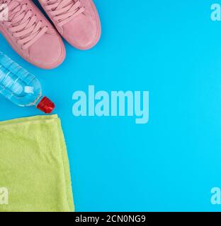 folded green terry towel and a transparent bottle of water on a blue background Stock Photo