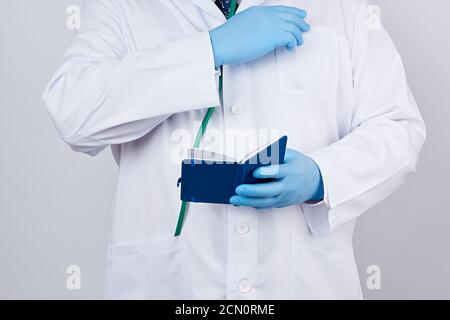 male doctor in a white coat with buttons holding a open blue paper notebook Stock Photo