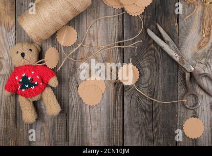 coil of brown rope, paper tags and old scissors on a gray wooden background Stock Photo