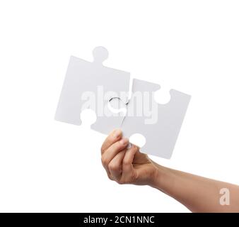 female hand holds two large paper empty white jigsaw puzzles isolated on white background Stock Photo