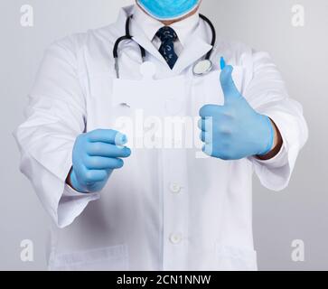 doctor in a white medical coat and blue rubber gloves holds a white paper puzzle