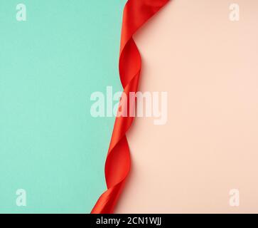 twisted silk red ribbon on a green-beige background Stock Photo