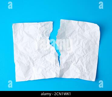 crumpled white sheet of paper torn in two on a blue background Stock Photo