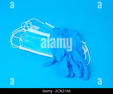 disposable gloves and stack of medical masks made of non-woven material with white rubber bands on a Stock Photo
