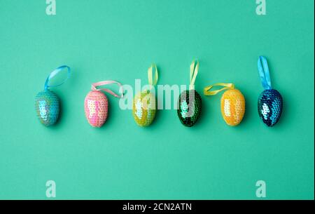 multicolored decorative Easter eggs decorated with sequins on a green background Stock Photo