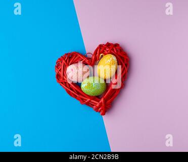 multicolored decorative Easter eggs decorated with sequins on a blue purple background Stock Photo