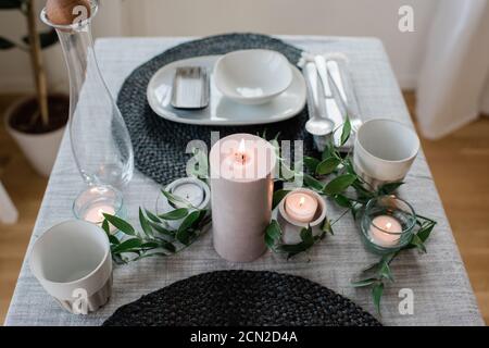 large candle on a romantic dinner table set up at home for two Stock Photo
