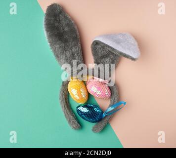 multicolored decorative Easter eggs decorated with sequins and rabbit mask on the head with ears Stock Photo