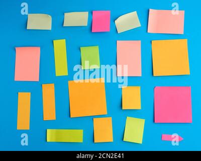 multicolored paper stickers of different shapes on a blue background Stock Photo