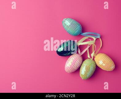 multicolored decorative Easter eggs decorated with sequins on a pink background Stock Photo