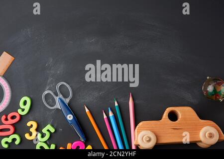 wooden multi-colored pencils, plastic numbers, scissors, wooden toy car on a black background Stock Photo