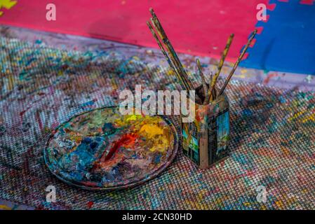 Paint palette and paintbrushes in water on the ground, no people Stock Photo